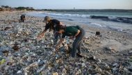 (Files) People look through plastic and other debris washed ashore at Kedonganan Beach near Denpasar on Indonesia's resort island of Bali on March 19, 2024. (Photo by Sonny Tumbelaka / AFP)
 