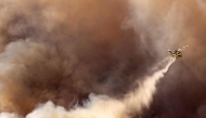 A fire helicopter makes a drop over the Mountain Fire as it scorches acres, the wildfire fueled by strong Santa Ana winds, in Moorpark, California, on November 7, 2024. (Photo by Etienne Laurent / AFP) / 