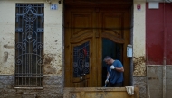 A man cleans his doorstep in Paiporta, south of Valencia, eastern Spain, on November 13, 2024 in the aftermath of deadly flooding. Photo by JOSE JORDAN / AFP