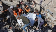 People and rescures carry the covered body of a preson pulled from the rubble of a house destroyed in an Israeli strike on al-Jalaa street in central Gaza City on November 18, 2024. (Photo by Omar Al-Qattaa / AFP)