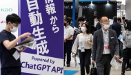 This file photo taken on May 10, 2023 shows visitors walking past a sign (L) promoting ChatGPT, a hugely popular language app that has sparked a rush in artificial intelligence technology, during the three-day 7th AI Expo, part of NexTech Week Tokyo 2023, Japan's largest trade show for artificial intelligence technology companies, at Tokyo Big Sight. Photo by Richard A. Brooks / AFP