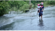 A woman holding a child in her arm wades through floodwater on a waterlogged road in Gampaha, Sri Lanka, on November 20, 2024. (Photo by Gayan Sameera/Xinhua)