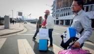 Shoppers walk across the street with their purchases near the US-Mexico border in San Ysidro, California, on November 26, 2024. (Photo by Sandy Huffaker / AFP)
