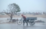 A man pulls his three-wheeler cart amid heavy wind and rainfall at the Marina Beach in Chennai on November 30, 2024, ahead of the landfall of cyclone Fengal in India's state of Tamil Nadu. Photo by R.Satish BABU / AFP