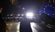 A protester waves a European Union flag in front of police during the fifth straight night of demonstrations against the government's postponement of EU accession talks until 2028, in central Tbilisi early on December 3, 2024. Photo by Giorgi ARJEVANIDZE / AFP.