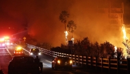 Firefighters work as the Franklin Fire burns near a building on December 10, 2024 in Malibu, California. Photo by MARIO TAMA / GETTY IMAGES NORTH AMERICA / Getty Images via AFP