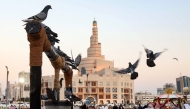 Pigeons stand on a decorative water well outside the Bazar Souq Waqif, with the Fanar mosque and the Abdulla Bin Zaid Al-Mahmoud Islamic Cultural Center in the background, in Doha on December 5, 2024. (Photo by KARIM JAAFAR / AFP)
