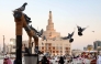 Pigeons stand on a decorative water well outside the Bazar Souq Waqif, with the Fanar mosque and the Abdulla Bin Zaid Al-Mahmoud Islamic Cultural Center in the background, in Doha on December 5, 2024. (Photo by KARIM JAAFAR / AFP)
