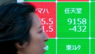 A woman walk past an electronic board showing the numbers of Nintendo's stock price (top, R) on the Tokyo Stock Exchange along a street in central Tokyo on January 17, 2025. Photo by Kazuhiro NOGI / AFP