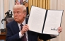 US President Donald Trump holds up an executive order he just signed to strenghten American leadership in digital financial technology, in the Oval Office of the White House in Washington, DC, on January 23, 2025. (Photo by Roberto Schmidt / AFP)