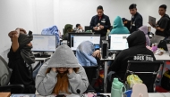 Workers sit at their desks during a raid by agents of the Presidential Anti-Organised Crime Commission (PAOCC) and the National Bureau of Investigation at an office of a suspected online scam farm in Manila on January 31, 2025. Photo by JAM STA ROSA / AFP