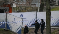 Police officers walk near a police fence blocking off an investigation area at the 