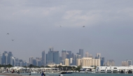 High-rise buildings of the Doha skyline are pictured before men fishing with rods off a pier in the city's harbour on February 17, 2025. (Photo by KARIM JAAFAR / AFP)
