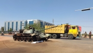 A truck drives past a Sudanese army tank at the entrance of Wad Madani in Sudan's al-Jazira state on February 20, 2025, after the regular army forces reclaimed the area from its rival Rapid Support Forces (RSF) last month. Wad Madani -- the capital of pre-war breadbasket Jazira state -- became a fierce battleground when RSF forces descended on the city in December 2023, forcing hundreds of thousands to flee amid reports of summary executions and systematic violence. (Photo by AFP)
