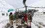 In this handout photograph taken on March 1, 2025 and released by the Department of Information and Public Relations (DIPR) Uttarakhand, security personnel carry a victim onto a helicopter during a rescue operation, a day after an avalanche hit a Border Roads Organisation (BRO) construction camp, as workers remain trapped under snow and debris near Mana village in the Chamoli district of India's Uttarakhand state. Photo by Department of Information and Public Relations (DIPR) Uttarakhand / AFP