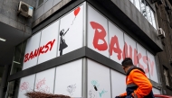 A roadsweeper passes by a gallery where an exhibition of the famous elusive artist Banksy is showcased in Belgrade on February 26, 2025. Photo by Andrej ISAKOVIC / AFP