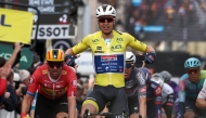 Soudal Quick-Step's Belgian rider Tim Merlier (C) wearing the overall leader's yellow jersey celebrates as he crosses the finish line to win the 2nd stage of the Paris-Nice cycling race, 183,9 km between Montesson and Bellegarde, on March 10, 2025. (Photo by Anne-Christine POUJOULAT / AFP)
