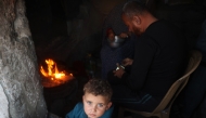 A child looks on as his family prepares a fast-breaking iftar meal in the Bureij camp for Palestinian refugees in the central Gaza Strip on March 11, 2025 during the Muslim holy fasting month of Ramadan. (Photo by Eyad BABA / AFP)