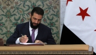 Syria's interim President Ahmad al-Sharaa signs the country's constitutional declaration, which will be enforced throughout a five-year transitional period, at the presidential palace in Damascus on March 13, 2025. (Photo by Bakr Alkasem / AFP)
