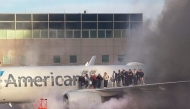 This image courtesy of Branden Williams shows passengers standing on the wing of an American Airlines plane as they are evacuated after it caught fire while at a gate at Denver International Airport in Denver, Colorado, March 13, 2025. (Photo by Branden Williams / Courtesy of Branden Williams / AFP) 