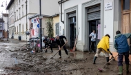 Residents and volunteers clean up mud and debris in a flooded street in Sesto Fiorentino, on March 15, 2025, one day after heavy rain hit the Florence region. (Photo by Federico Scoppa / AFP)