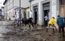 Residents and volunteers clean up mud and debris in a flooded street in Sesto Fiorentino, on March 15, 2025, one day after heavy rain hit the Florence region. (Photo by Federico Scoppa / AFP)