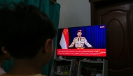 Yemenis in Sanaa watch a televised statement by the Houthi military spokesman Yahya Saree announcing the rebel group launched an attack on a US aircraft carrier in the Red Sea on March 16, 2025. (Photo by Mohammed HUWAIS / AFP)