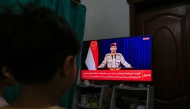 Yemenis in Sanaa watch a televised statement by the Huthi military spokesman Yahya Saree announcing the group launched an attack on a US aircraft carrier in the Red Sea on March 16, 2025. Photo by Mohammed HUWAIS / AFP.