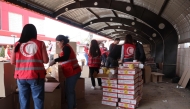 A handout picture provided by Syria's Kurdish Red Crescent shows members of the emergency charity group preparing humaintarian aid boxes, in the northeastern city of Qamishli on March 16, 2025. (Photo by Kurdish Red Crescent / AFP) 