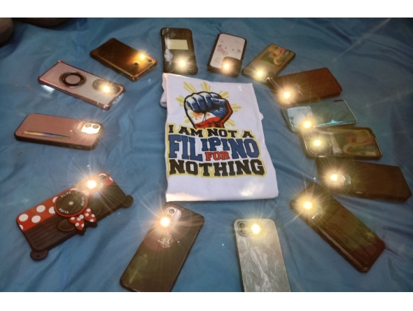 Filipino migrant workers turn on their phone flashlights and place them in a circle around a clenched fist symbol to express support for former Philippine president Rodrigo Duterte, at Repulse Bay in Hong Kong on March 16, 2025. (Photo by Purple Romero / AFP)