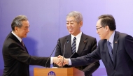 China's Foreign Minister Wang Yi (L) and South Korea's Foreign Minister Cho Tae-yul (R) shake hands as Japan's Foreign Minister Takeshi Iwaya looks on during a joint press conference after their meeting during the 11th Trilateral Foreign Minister's Meeting (Japan-China-ROK) in Tokyo on March 22, 2025. (Photo by Rodrigo Reyes Marin / POOL / AFP)
