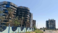 A vehicle moves along a road past (L) the heavily damaged building that housed the headquarters of the Central Bank of Sudan is pictured in Khartoum's Muqrin neighbourhood on March 22, 2025. (Photo by AFP)
