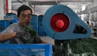 A man works at a Christmas tree factory for export and domestic markets in Jinhua, China's eastern Zhejiang province on April 11, 2025. (Photo by ADEK BERRY / AFP)
