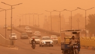 Motorists drive their vehicles along a highway through low visibility conditions as a massive dust storm advances on Iraq's central city of Najaf on April 14, 2025. (Photo by Qassem al-KAABI / AFP)