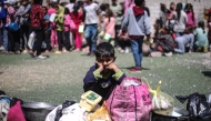 A Palestinian child waits to receive a hot meal at a free food distribution point at the Nuseirat refugee camp in the central Gaza Strip on April 19, 2025. (Photo by Eyad BABA / AFP)