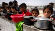 Children queue with pots to receive charity meals from a kitchen in Beit Lahia in the northern Gaza Strip on April 24, 2025. Photo by Bashar TALEB / AFP