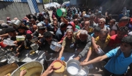 Palestinians queue for a hot meal at a charity kitchen run by the United Nation's World Food Programme (WFP) at the Nuseirat refugee camp in the central Gaza Strip on April 26, 2025. (Photo by Eyad Baba / AFP)