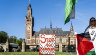 A demonstrator stands beside a placad reading 