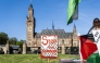 A demonstrator stands beside a placad reading 