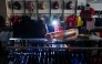 A saleswoman at a sports store works with a light on her head in Burgos on April 28, 2025, during a massive power cut affecting the entire Iberian peninsula and the south of France. (Photo by CESAR MANSO / AFP)

