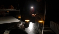 A waiter gives change by the light of her phone in a bar during a massive power cut affecting the entire Iberian peninsula and the south of France, in Hernani on April 28, 2025. (Photo by Ander Gillenea / AFP)