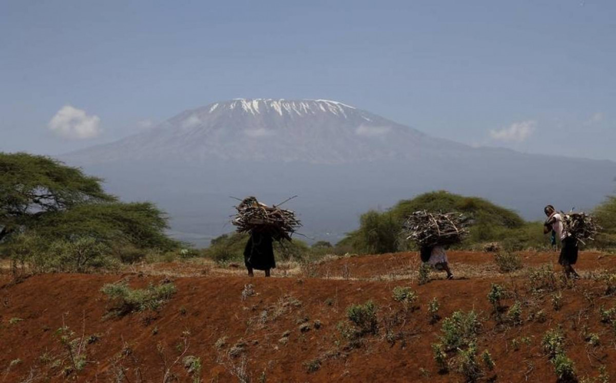 Mount Kilimanjaro is seen behind maasai women carrying firewood outside Amboseli National Park, southeast of Kenya's capital Nairobi, March 26, 2016. REUTERS/Thomas Mukoya