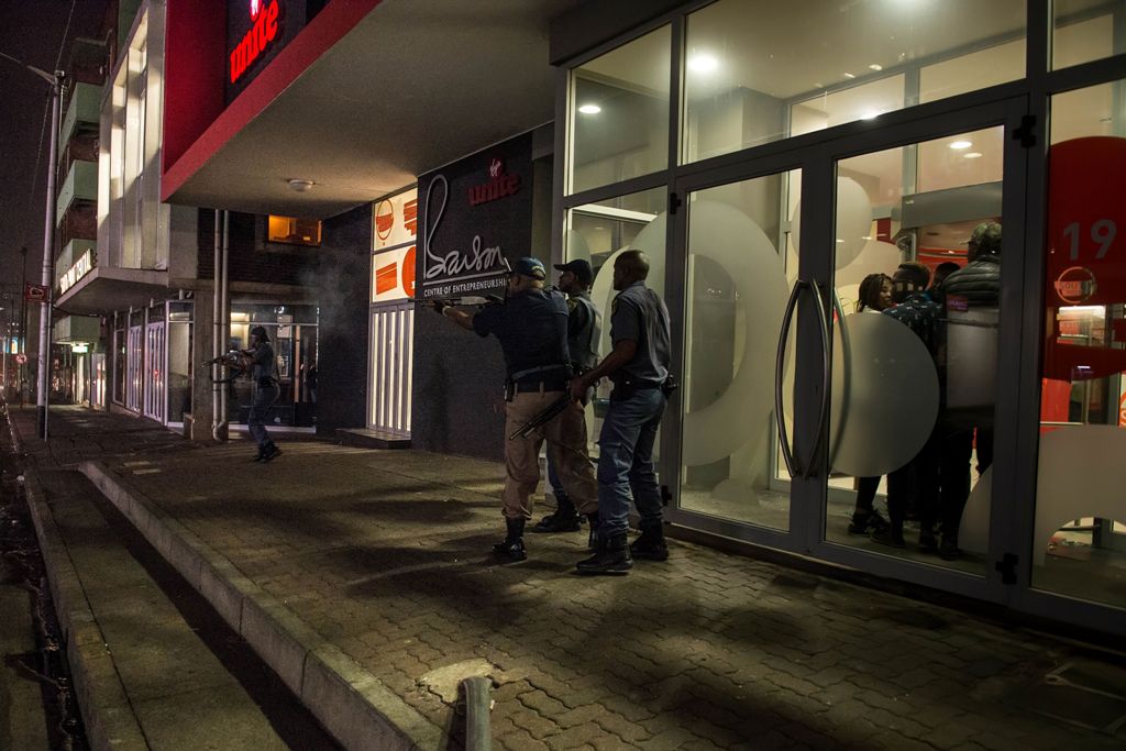 South African policemen deploy in the Braamfontein district of Johannesburg on October 14, 2016 during riots involving university students protesting over planned hikes in tuition fees. / AFP / MUJAHID SAFODIEN