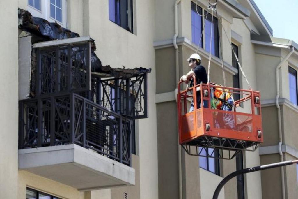 Workmen examine the damage at the scene of a 4th-story apartment building balcony collapse in Berkeley, California June 16, 2015. REUTERS/Elijah Nouvelage.