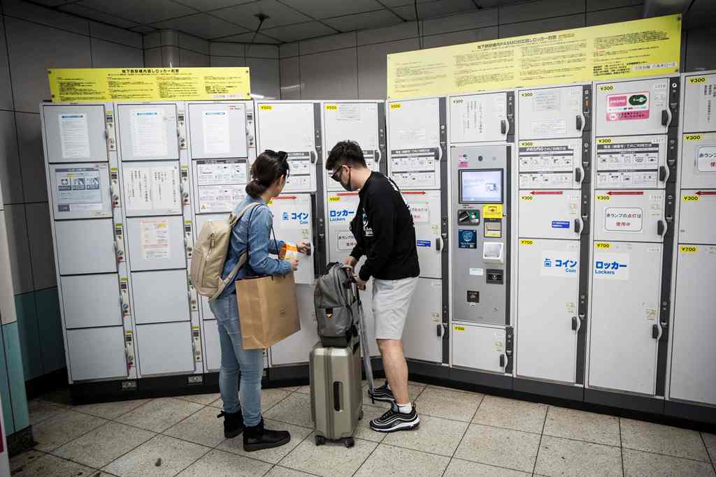 In this picture taken on September 4, 2017, a couple use a coin locker in Roppongi subway station in Tokyo.  AFP / Behrouz MEHRI
