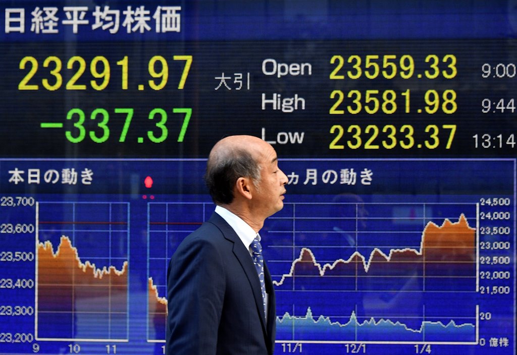 A pedestrian walks past a stock market indicator board in Tokyo, Japan, 30 January 2018. EPA / FRANCK ROBICHON