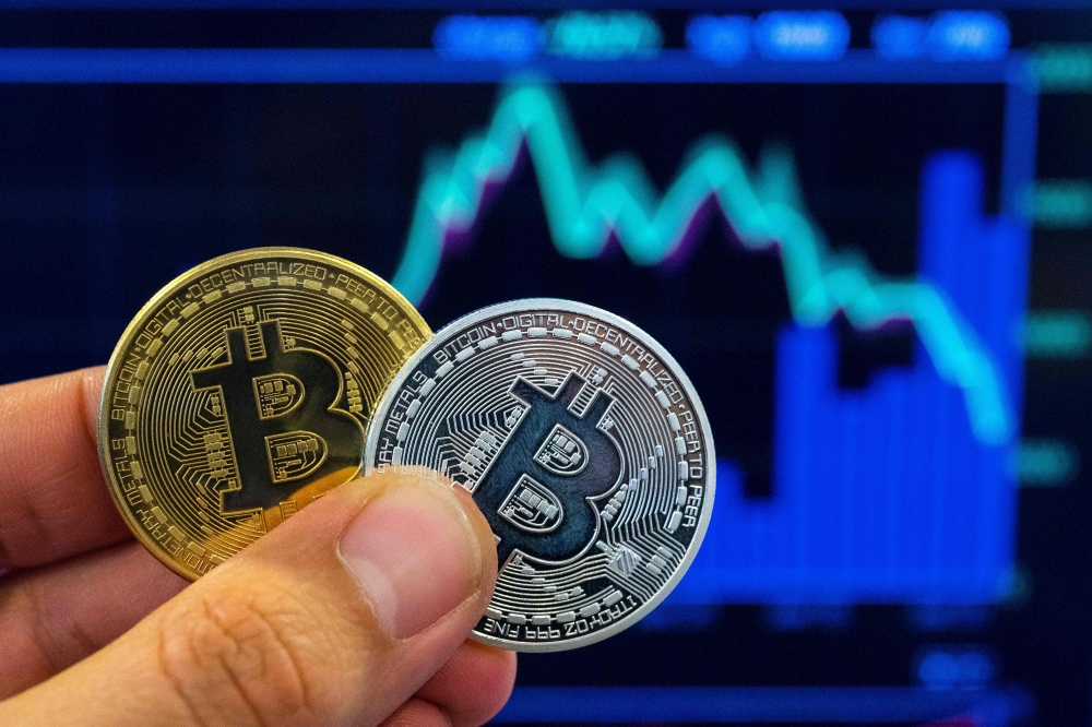 A picture taken on February 6, 2018 shows a person holding a visual representation of the digital crypto-currency Bitcoin, at the 