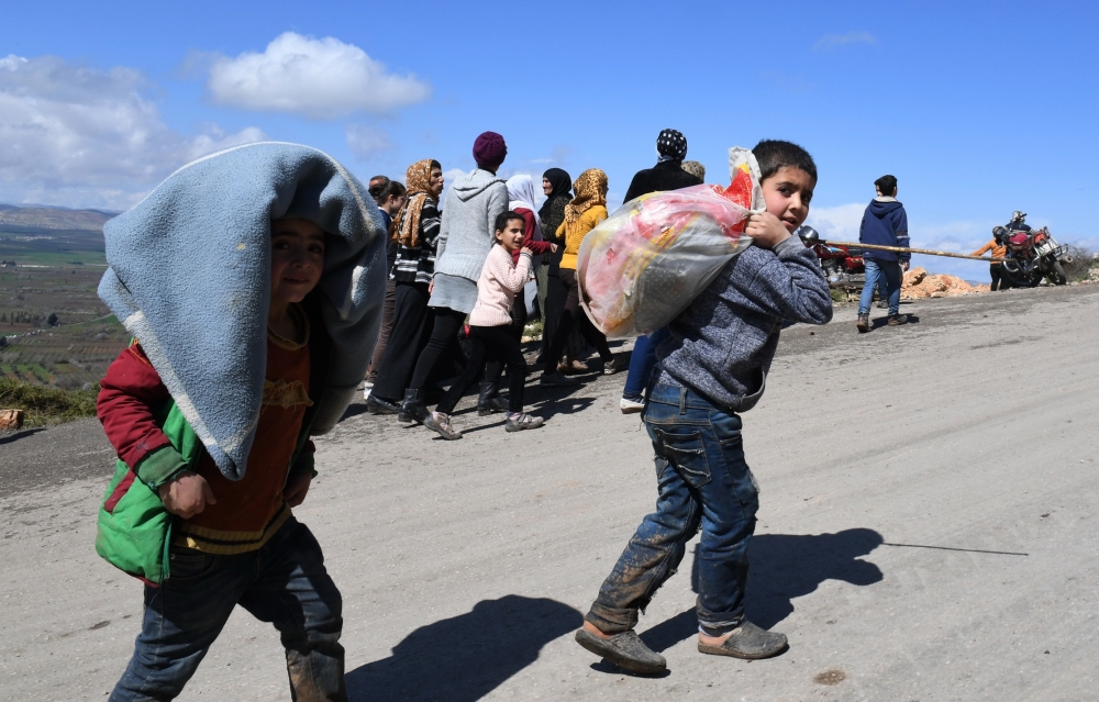 Civilians fleeing the city of Afrin in northern Syria walk at the mountainous road of al-Ahlam while heading towards the check point in az-Ziyarah, in the government-controlled part of the northern Aleppo province, on March 16, 2018.  AFP / George OURFALI