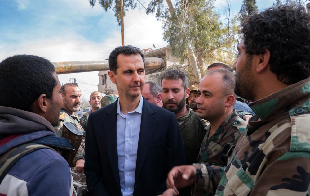 A handout picture released by the official Facebook page of the Syrian Presidency on March 18, 2018, shows Syrian President Bashar al-Assad (C) talking with government troops in Eastern Ghouta