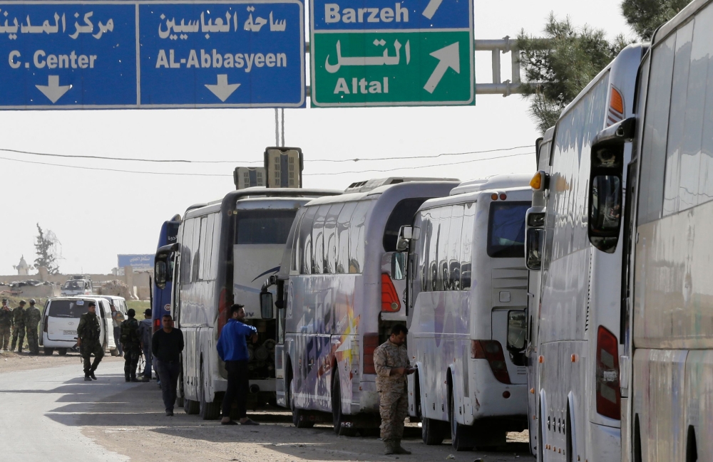 A convoy transporting Syrian civilians and rebel fighters evacuated from Eastern Ghouta arrives in a government-held area at the entrance of Harasta on the outskirts of the capital Damascus, on March 26, 2018.  AFP / LOUAI BESHARA
